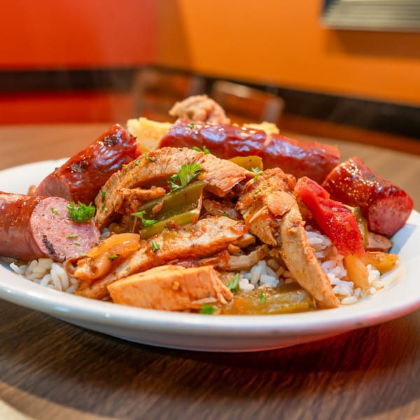 Flying Mango's southern jambalaya with chicken, sausage, peppers, and rice on a white plate.